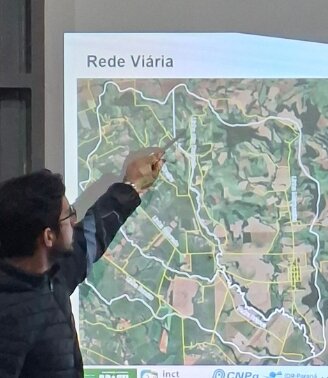 Pesquisador apontando para o mapa da rede viária da bacia do Rio Dourado projetado durante a apresentação